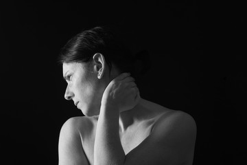 middle-aged woman with pain in the neck on black background