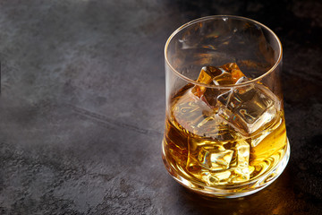 Glass of whiskey with ice cubes (on the rocks) on black background. Copy space