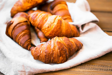 Freshly baked croissants on kitchen napkin on wooden table