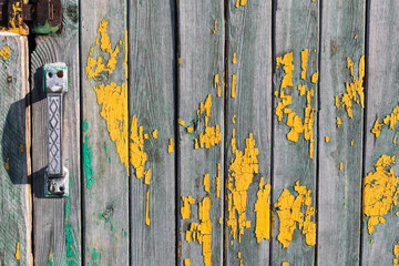 Wooden background with yellow peeling paint stains