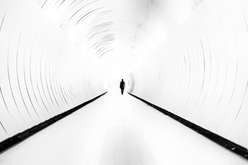 Silhouette of man walking in bright tunnel