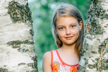 Portrait of cheerful cute little girl near the birch