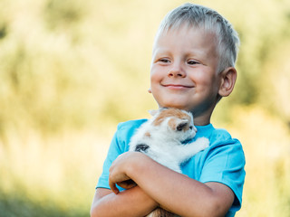 Little boy at countryside holding his lovely fluffy kitty cat