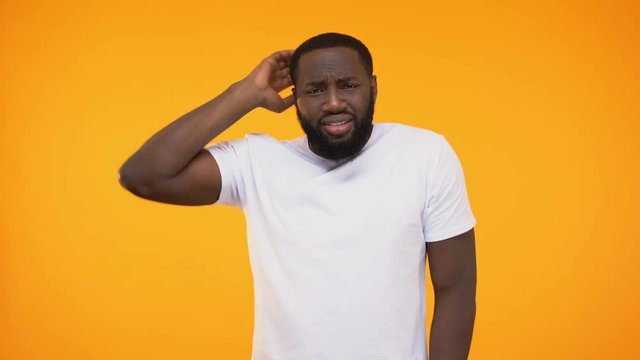 Young african american man shrugging in confusion, isolated on yellow background