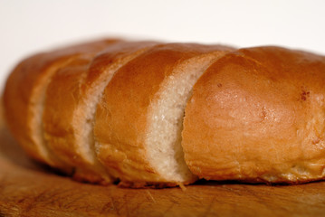 Fresh bread cut into pieces on a wooden board closeup. Shallow depth of field