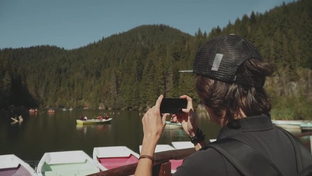 Man traveler takes picture of lake with phone camera. Tourist makes photo for social network or travel blog,close-up,slow motion.