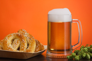 Pint of beer with ingredients for homemade beer on red with pretzel
