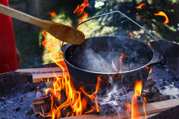 Tourist bowler with food on bonfire, cooking in the hike, outdoor activities. Preparation of pilaf.