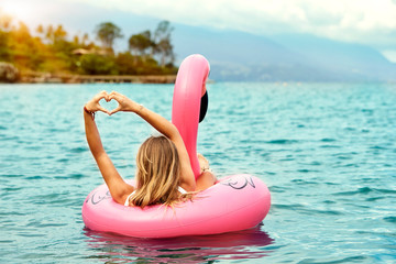 Blond woman loving her flamingo toy in sea