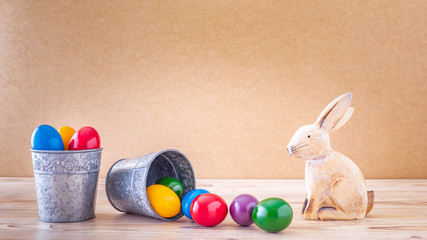 Zwei silberne Becher mit bunte Ostereier und Osterhase Vor einem Holz Hintergrund