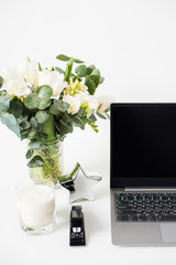 Hipster bloggers work place, laptop and flowers on white tabletop