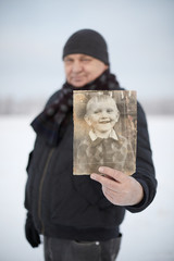 Aged man with his photo as child