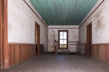 Hallway leading to stairwell in old farmhouse with wainscoting and green ceiling