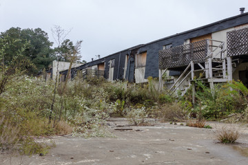 Remains of abandoned apartment complex with overgrown grass