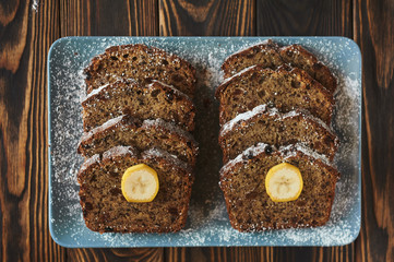 sliced homemade brown cake at blue dish decorated with two banana pieces