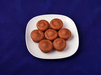 Brown muffins on a white plate, with blue background
