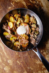 A delicious nourishing dinner of fried potatoes, meat, vegetables and soft chicken eggs served in a frying pan.