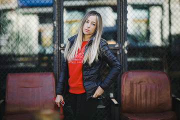 Plakat Streetstyle female portrait. Blonde woman in leather jacket poses on the street outside