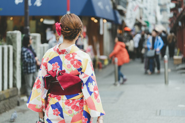 Fototapeta premium Young girl wearing Japanese kimono standing in front of Sensoji Temple in Tokyo, Japan. Kimono is a Japanese traditional garment. The word 