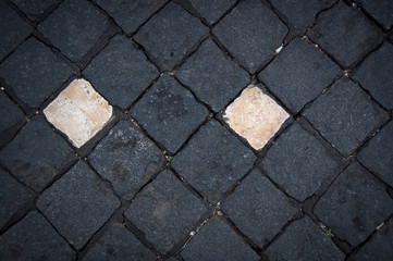 Playing with different shapes and patterns of a cobbled streets of Lisbon (Portugal). Two white cobblestones surrounded by black ones.