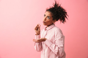 Beautiful young african woman posing isolated over pink wall background imagine that she drinking tea.