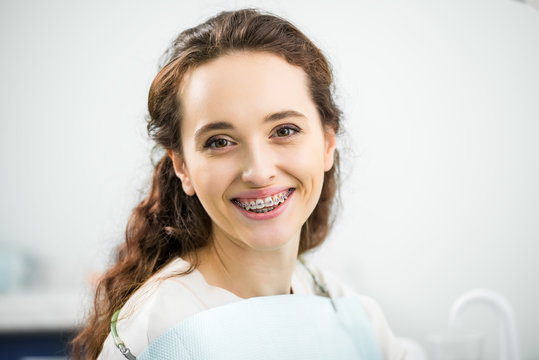 happy woman with braces on teeth smiling in dental clinic