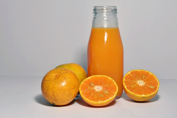Many tangerine and tangerine juice in a bottle with white background.