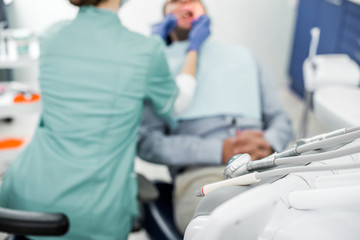 selective focus of dental instruments with dentist examining patient on background