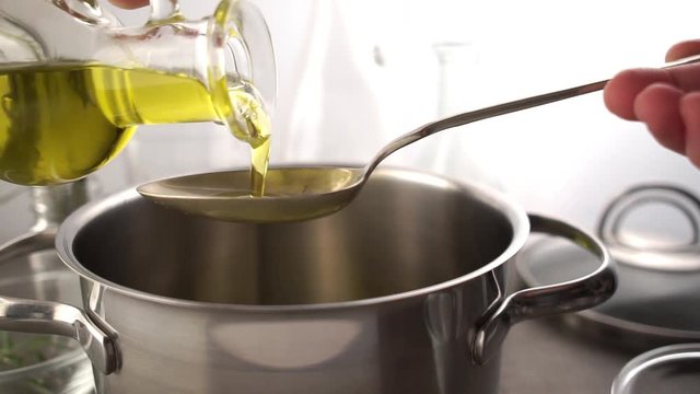 Cooking meal in a pot. Bottle of Extra virgin oil pouring in to pot for cooking meal. Healthy food. Main course Close up. Slow motion video footage. Slowmo. Slow-mo
