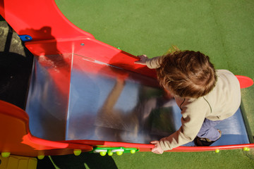Cute caucasian child boy having fun to play slider in the playground