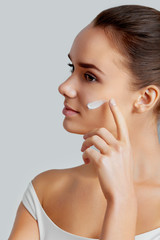 Close-up portrait of a beautiful smiling woman with cream on her face