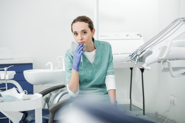 selective socus of pensive female dentist sitting in dental clinic