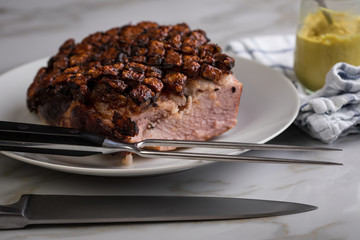 Deutscher Krustenbraten aus Schweinefleisch mit Senf auf Teller mit Küchenmesser und Fleischgabel auf Marmor Hintergrund