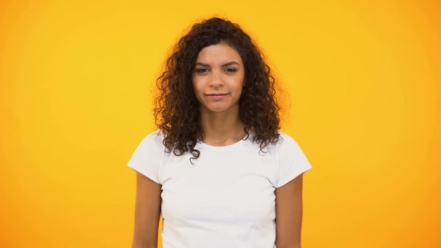 African american girl screaming to camera against yellow background, protest