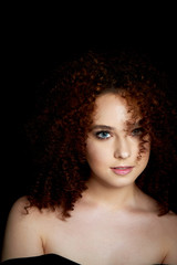 A girl with lush curly red hair. Open shoulders. Smiles