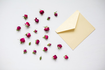 Envelope and dry roses on a light background. Love invitation for a date. Top view and flat lay.