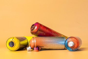 used colorful spray cans isolated on orange background b