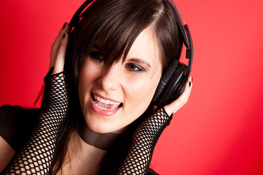 Young Woman with Headphones Listening to Music and Singing
