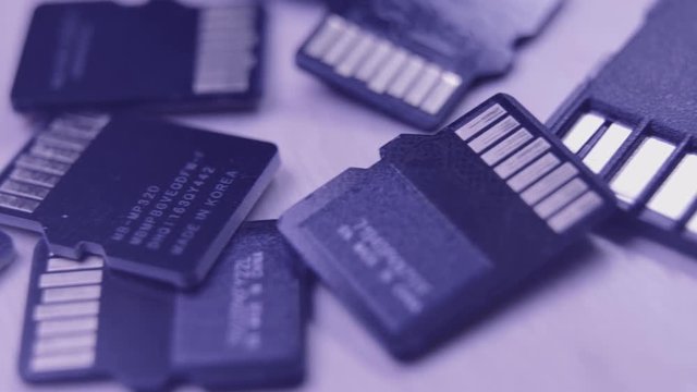 Group of MicroSD cards over a wooden table. Macro and tracking shot. Desaturated blue style