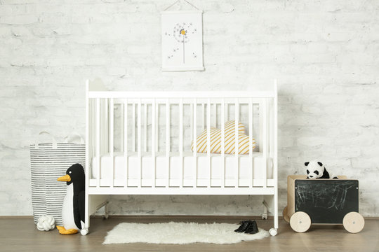 White wooden baby crib and toys in the room, Scandinavian inspired kids room interior