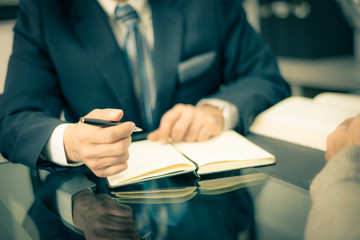 Man in a suit holding a pen and taking notes in a formal meeting