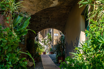Bogendurchgang ums&auml;umt von Pflanzen einer mittelalterlichen Gasse in der Altstadt von Cervo in Ligurien Italien