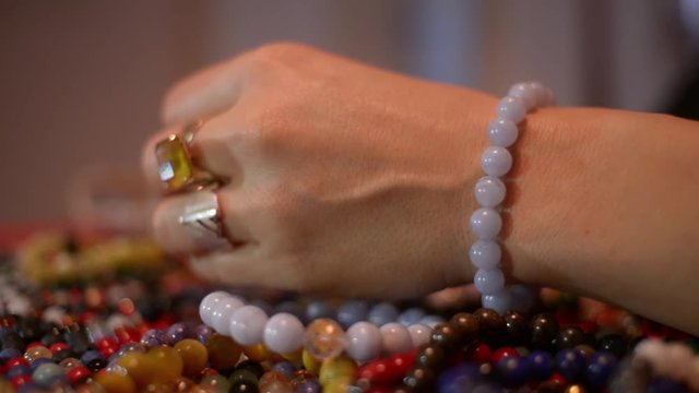 Women's hands measure Coral Bracelets on a Table