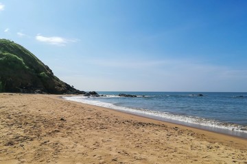 Green hill on the sea beach and blue sky.