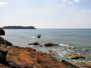 Fototapeta na wymiar Rocky sea shore on the background of a green island