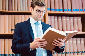 Rechtsanwalt in seiner Kanzlei liest in dicken Büchern und denkt nach 