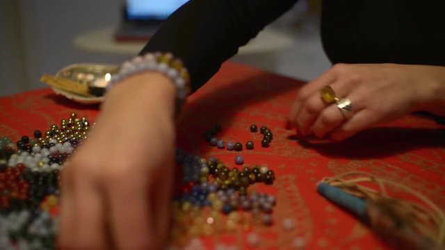 Women's hands works with Corals to make a Coral Bracelets on a Table