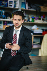 Successful businessman holds his phone and smiles