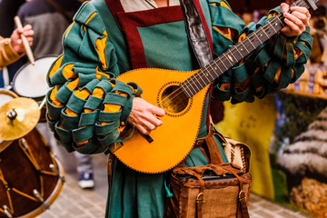 Medieval troubadour playing an antique guitar. - obrazy, fototapety, plakaty