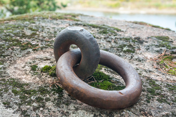 Closeup of a rusty old mooring loop fastened in a rock, used to tie up boats in the river